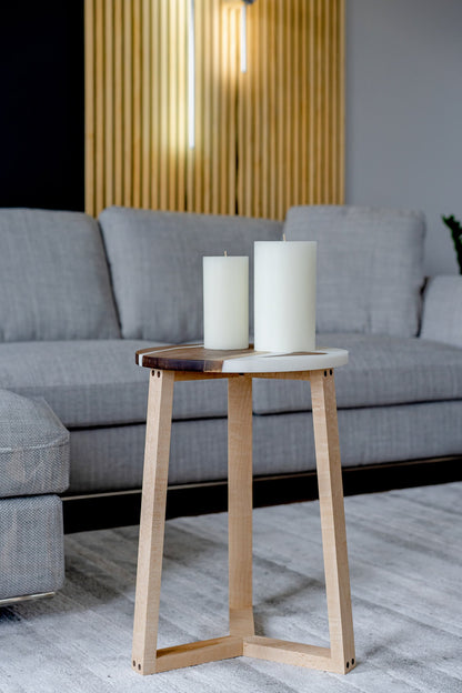 Image showing an elegant epoxy resin and walnut side table with contrasting maple legs. This round table, with its white epoxy encasing a rich walnut slab top, demonstrates unique wood grain patterns, illustrating its individual character. Perfect for living spaces or offices.