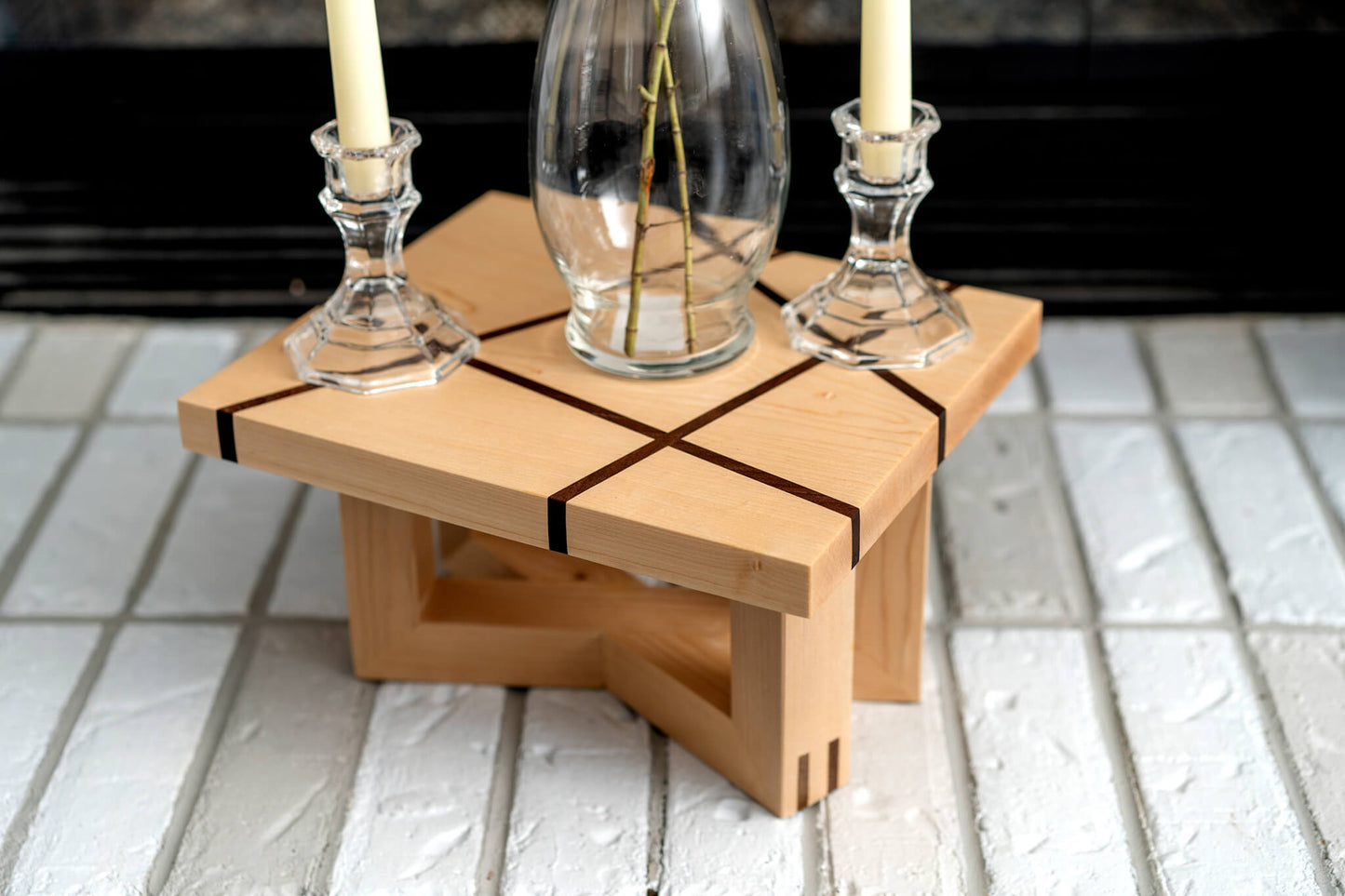 Photograph illustrates a Maple candle riser, enriched with Walnut detail lines. The stand, has Pine and Walnut legs, displaying the detailed texture of the wood grain through its Hard-wax oil finish.