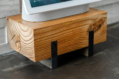 Image of a stained Pine plant stand featuring an electronic device against a rustic brick wall. The stand, finished with hard-wax oil, showcases the richness of wood grain and its elevated design.