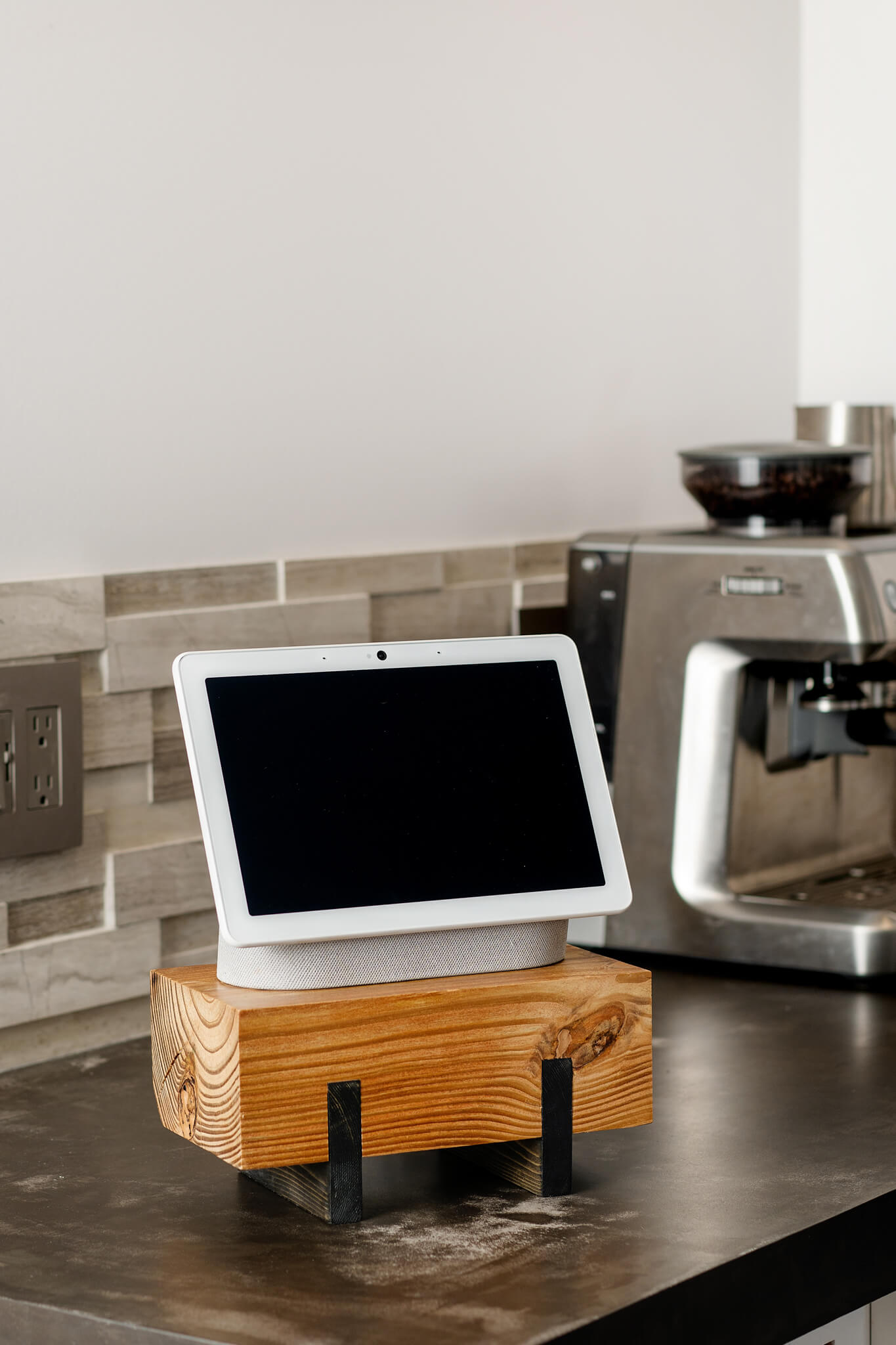 Image showcasing a multi-purpose Pine plant stand against a brick wall. The stand, finished with a stain and hard-wax oil, displays an electronic device. The elevated design and visible grain pattern of the wood highlights its rustic charm.