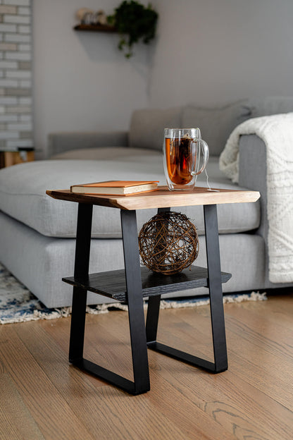 Image of a live edge side table handcrafted from Chocolate Brown Walnut. The table has black metal legs and features a rich, unique wood grain pattern, showcasing the natural beauty and uniqueness of the Walnut wood